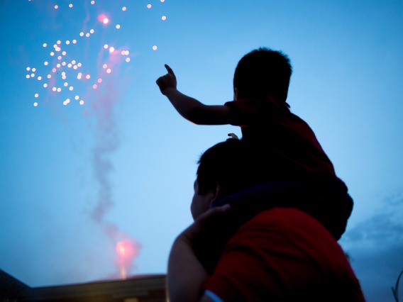 Silhouette of a father with son on shoulders watching fireworks