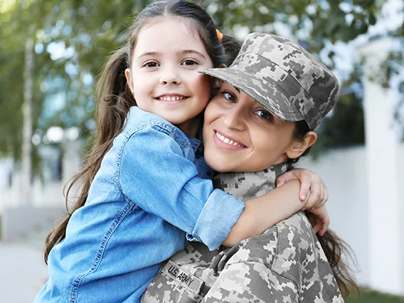 A woman in service hugging her young child. 